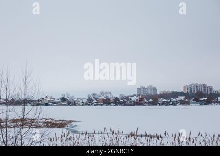 Ellings près de la rivière gelée en toile de fond de la ville d'Ukrainka. Sécher les roseaux à l'eau. Paysage d'hiver. Copier l'espace Banque D'Images