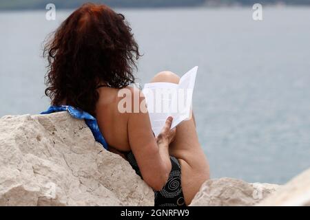 Femme lisant un livre à la mer. Piran. Slovénie. Banque D'Images