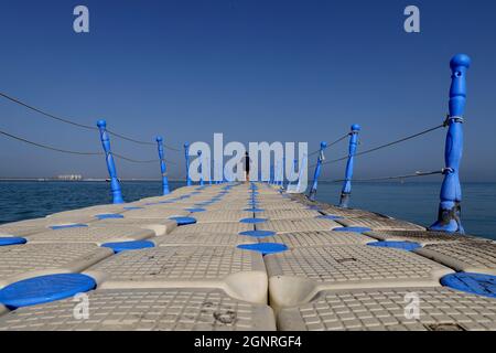 Femme marchant sur un ponton en plastique flottant dans la mer. Plage Al Hamra sur le golfe Arabo-Persique à Ras Al Khaimah. Émirats arabes Unis. Banque D'Images