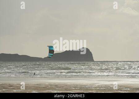 Gower, Swansea, Royaume-Uni. 27 septembre 2021. Météo au Royaume-Uni : une journée d'automne venteuse de soleil et de douches à Llangennith Beach sur la péninsule de Gower. Un kite surfeur profite de la brise côtière raide. La tête de Worms promontoire est représentée en arrière-plan à la baie de Rhossili. Credit: Gareth Llewelyn/Alamy Live News Banque D'Images