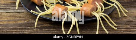 bannière de spaghetti avec saucisses sous forme d'araignées. Bonne nourriture pour enfants pour Halloween sur fond de bois Banque D'Images