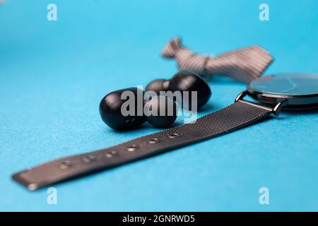 casque sans fil noir et montre sur fond bleu. Banque D'Images