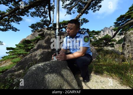 (210927) -- HEFEI, 27 septembre 2021 (Xinhua) -- Hu Xiaochun vérifie les poteaux de soutien du PIN de salutation dans la région pittoresque de la montagne Huangshan, dans la province d'Anhui, en Chine orientale, le 26 septembre 2021. La montagne Huangshan, l'un des endroits les plus célèbres de Chine, est un site classé au patrimoine mondial de l'UNESCO dans la province d'Anhui en Chine orientale et un géoparc mondial. Salutation Pine est un monument célèbre dans la montagne Huangshan. L'arbre, qui grandit des rochers avec une longue branche s'étendant sur l'embouchure d'une grotte, a obtenu le nom principalement parce qu'il semble accueillir n'importe qui qui arrive sur la scène. On le croit Banque D'Images