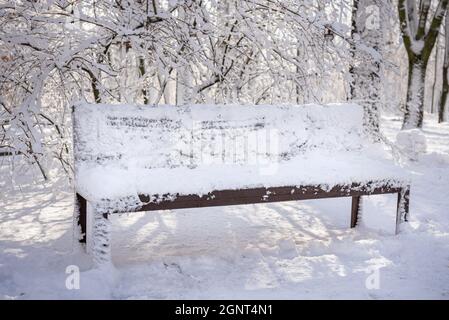 Banc de parc couvert de neige en hiver. Une journée d'hiver ensoleillée. Parc municipal couvert de neige, chute de neige Banque D'Images