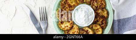 Bannière de tranches de courgettes frites avec sauce à la crème aigre sur l'assiette. Courgettes frites aux herbes pour le dîner sur fond blanc. Haut wiev Banque D'Images