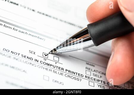 Personne vérifiant la case sexe masculin sur un formulaire de document avec stylo à bille noir Banque D'Images