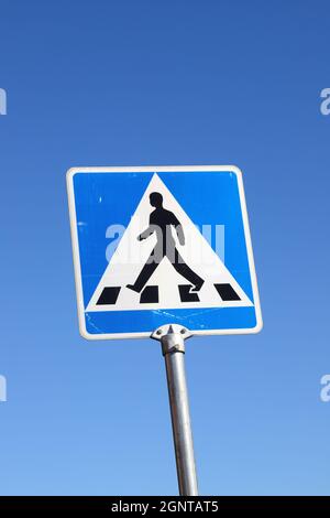 Vue à angle bas d'un panneau de signalisation de passage de côté isolé contre un ciel bleu clair. Banque D'Images