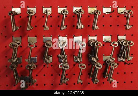 Limassol - Chypre - 20 septembre 2021 : clés non coupées dans un atelier de serrurier accroché sur fond rouge vif Banque D'Images