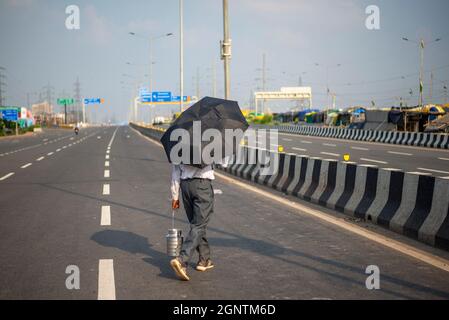 Ghaziabad, Inde. 27 septembre 2021. Un homme marche sur une route déserte lors d'une grève nationale contre les réformes agricoles à la frontière Delhi-Uttar Pradesh.des milliers d'agriculteurs indiens ont bloqué la circulation sur les routes principales et les lignes de chemin de fer à plusieurs endroits du matin, comme l'a appelé la fermeture de Samyukta Kisan Morcha (Farmer Union Body), un corps de parapluie de 40 syndicats d'agriculteurs a commencé, le blocus a été levé à 4 heures. (Photo de Pradeep Gaur/SOPA Images/Sipa USA) crédit: SIPA USA/Alay Live News Banque D'Images