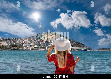 Vue arrière de fille en robe rouge et chapeau blanc montres Kusadasi ville. Banque D'Images