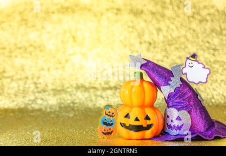 Photographie de concept représentant une tête de citrouille jack o lanterne d'halloween et un chapeau de sorcières pourpre avec un fantôme drôle souriant et des chauves-souris découpées en carton aga Banque D'Images