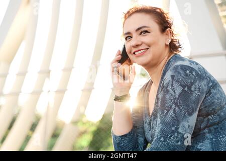riant femme mûre dans la ville parlant au téléphone. Banque D'Images