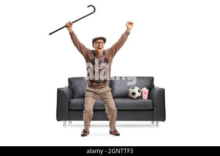 Homme senior sautant d'un canapé et applaudissant pour une équipe de football isolée sur fond blanc Banque D'Images