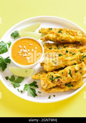 Brochettes de poulet grillées servies avec une sauce trempée aux arachides sur fond jaune. Vue rapprochée Banque D'Images