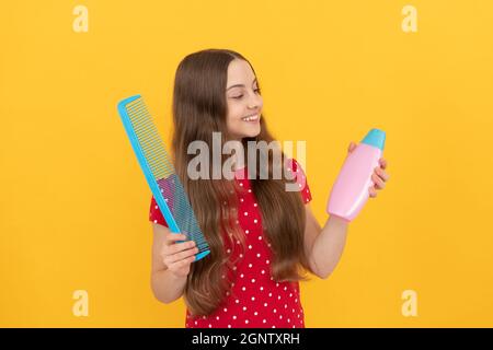 joyeux enfant peignant les cheveux longs. coiffeur. fille a la brosse à cheveux ondulée Banque D'Images