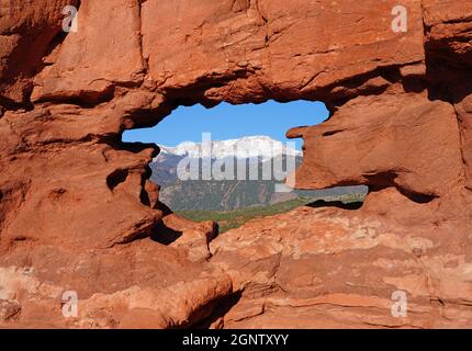 Vue sur le pic de Pikes à travers le trou dans la formation de roches rouges Siamese Twins dans le parc Garden of the Gods à Colorado Springs, Colorado, États-Unis Banque D'Images