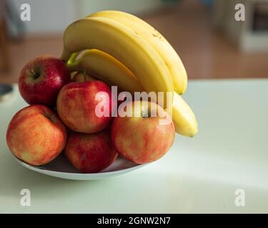 Pommes et bananes à l'échelle sur une table à la maison Banque D'Images