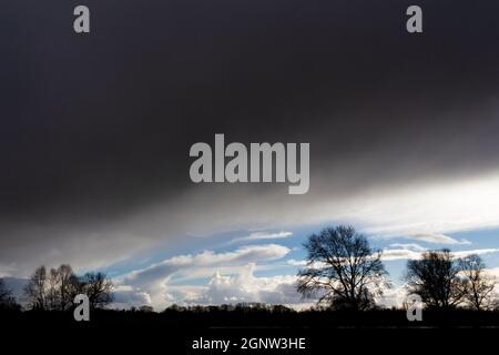 Un gros nuage lourd et foncé s'enfonce sur un paysage d'arbres Banque D'Images