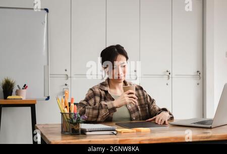 Photo rognée d'une femme asiatique travaillant ou apprenant sur un ordinateur portable à l'intérieur - cours ou formation, séminaire, concept en ligne d'éducation Banque D'Images