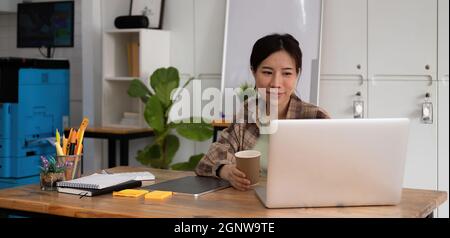 Des jeunes filles jeunes filles asiatiques souriantes visiophonie sur ordinateur portable. Bonne jolie femme étudiante regardant l'écran d'ordinateur regarder le webinaire ou faire le chat vidéo par Banque D'Images