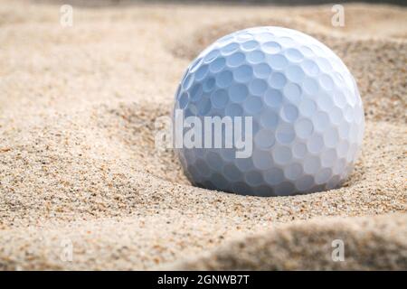 Close up balle de golf dans le sable bunker peu de profondeur de champ. Une balle de golf branché au fond de fosse de sable. Banque D'Images