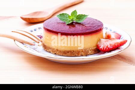Gâteau au fromage aux fraises avec des feuilles de menthe fraîche sur fond de bois. Focus sélectif de la profondeur de champ. Banque D'Images