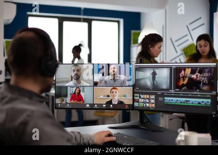 Directeur de l'éditeur vidéo senior parlant avec l'équipe créative lors d'une réunion Web en ligne sur le travail de montage vidéo par appel client. Homme qui reçoit des commentaires sur le film en utilisant le logiciel de post-production sur pc Banque D'Images