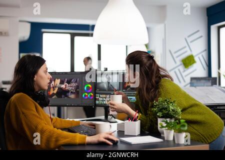 Collègues heureux parlant de montage de film créatif regarder des idées de production de film travailler dans le bureau de démarrage avec deux moniteurs. Projet d'édition vidéo pour femmes dans les logiciels de post-production Banque D'Images