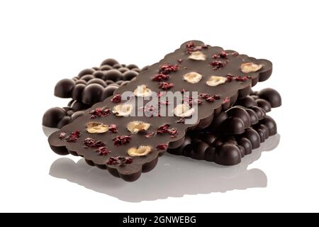 Chocolat brut foncé avec noix de haselnut et cerises lyophilisées sur fond blanc. Isoler Banque D'Images