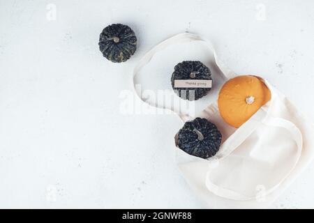 Décoration d'automne de citrouilles dans un sac écologique sur fond blanc avec les mots Thanksgiving. Thanksgiving, automne, concept zéro déchet. Vue de dessus.qual. Haute Banque D'Images