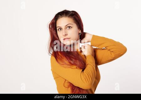 Portrait d'une femme hispanique dans un chandail orange et une belle expression avec ses bras. Banque D'Images