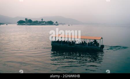 Un bateau de couleur orange sur le lac bleu Pichola pendant la lumière du jour à Udaipur, Rajasthan Banque D'Images