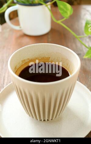 Tasse de café chaud avec des plantes géantes en marbre en arrière-plan Banque D'Images