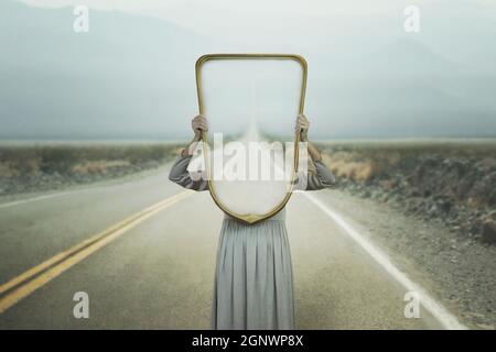 la femme se cache tenant un miroir devant son visage ; concept de chemin d'introspection Banque D'Images