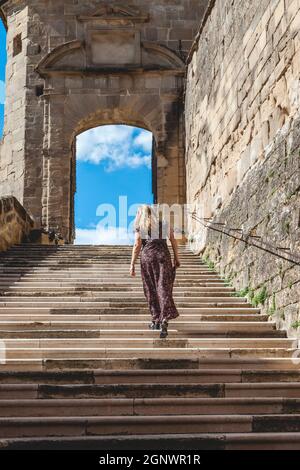 Femme en robe longue escalade les marches de l'abbaye de Saint Antoine France. Concept de destination touristique Banque D'Images