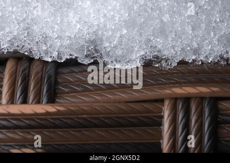 Mobilier de jardin en plastique glacé. Tissu tissé en rotin, mais synthétique. Le temps froid en extérieur a provoqué la formation d'une couche de neige ou de givre. Banque D'Images