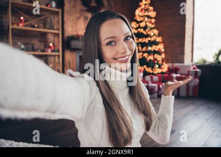 Photo portrait femme souriante portant un chandail tricoté à la maison prenant selfie montrant l'arbre de Noël Banque D'Images