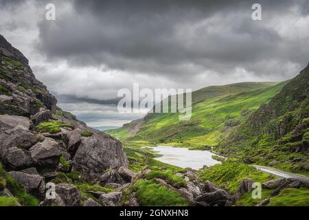 Vue panoramique sur les collines verdoyantes et un lac à Gap of Dunloe. Ciel orageux spectaculaire dans la vallée noire, l'anneau de Kerry, comté de Kerry, Irlande Banque D'Images