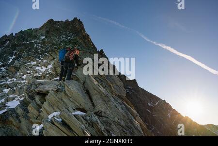 Vue arrière des grimpeurs avec sacs à dos à l'aide d'une corde fixe tout en montant haute montagne rocheuse. Hommes alpinistes escalade formation naturelle de roche Banque D'Images