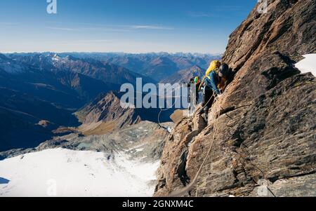 Femme grimpant la formation naturelle de roche et essayant d'atteindre le sommet de montagne.Au coucher ou au lever du soleil.Concept de l'escalade alpine.Crête de Studlgrat Banque D'Images