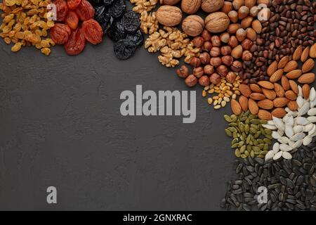 Différentes sortes de noix et de fruits secs. Diverses variétés de noix, de graines et de fruits secs sur fond d'ardoise noire. Vue de dessus avec espace de copie. Il Banque D'Images