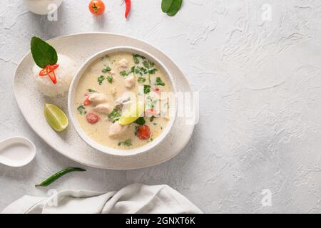 Soupe crémeuse épicée Tom Kha Gai à la noix de coco avec poulet, tomate cerise, lait de coco, kaffir, galangal, citronnelle, champignons. Cuisine thaïlandaise asiatique. Chic noix de coco Banque D'Images