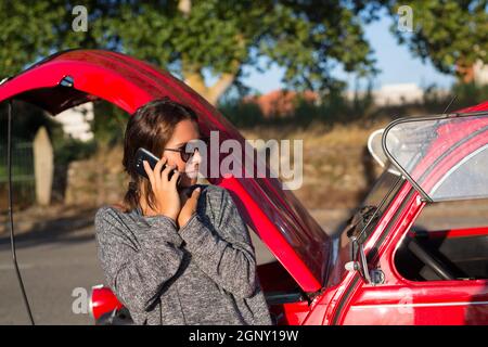 Femme sur un roadtrip ayant un problème avec sa vieille voiture Banque D'Images