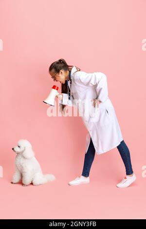 Portrait conceptuel de la jeune belle femme, vétérinaire avec chien de coolé blanc isolé sur fond rose studio. Soins pour animaux de compagnie, animaux chez l'homme Banque D'Images