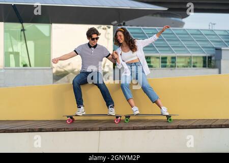 Un jeune couple de boxers s'amuse avec un skateboard en planche à repasser, dans un parc urbain Banque D'Images