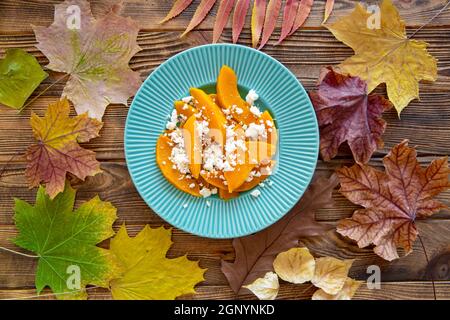 Salade d'automne avec potiron et feta, vue de dessus. Arrière-plan de feuilles colorées. Banque D'Images