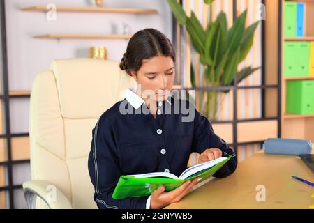 Portrait d'une fille dans un uniforme d'école avec un livre entre ses mains. L'enfant lit un manuel. Préparer une écolière pour une leçon ou un examen scolaire Banque D'Images