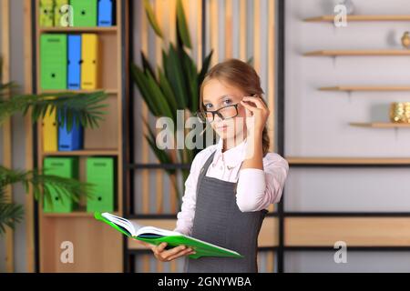 Portrait d'une fille dans un uniforme d'école avec un livre entre ses mains. L'enfant lit un manuel. Préparer une écolière pour une leçon ou un examen scolaire Banque D'Images