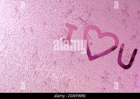 Image 3D , écrit '' Je vous aime 'sur verre de fenêtre avec des gouttes sur fond de couleur rose. Concept Saint Valentin, mariage Banque D'Images