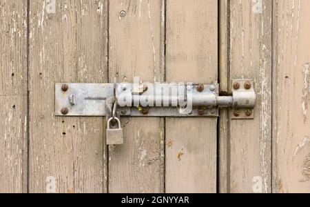 Gros plan d'une ancienne porte en bois abîmé avec de la peinture écaillée et un cadenas verrouillé. ROYAUME-UNI Banque D'Images